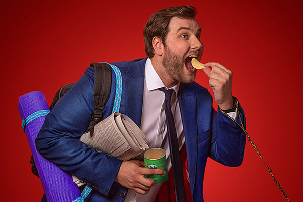 man carrying lots of luggage and eating pringles